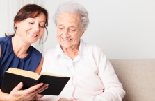 Provider of senior home care services in Edmonton reading to senior woman