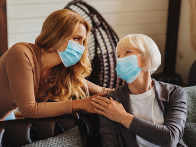 caregiver wearing face mask helping senior woman