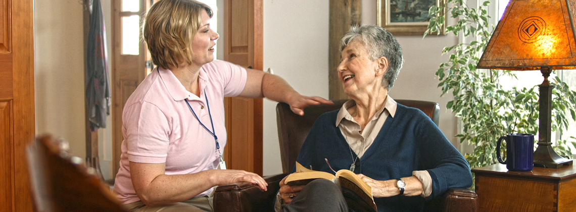provider of home care services in Berwick, NS discussing book with elderly woman