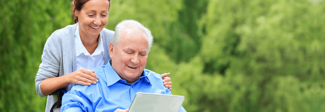 provider of personal care in Edmonton standing behind elderly man in wheelchair