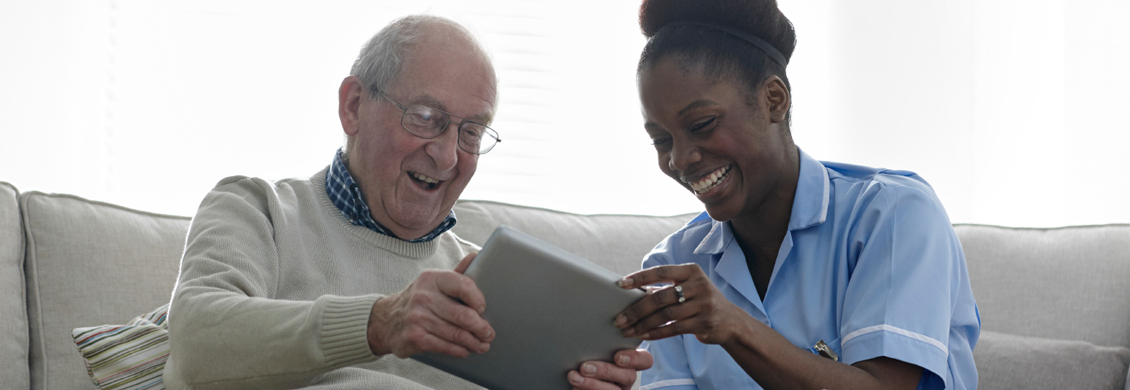 caregiver helping elderly man aging in place at Annapolis Valley use a tablet